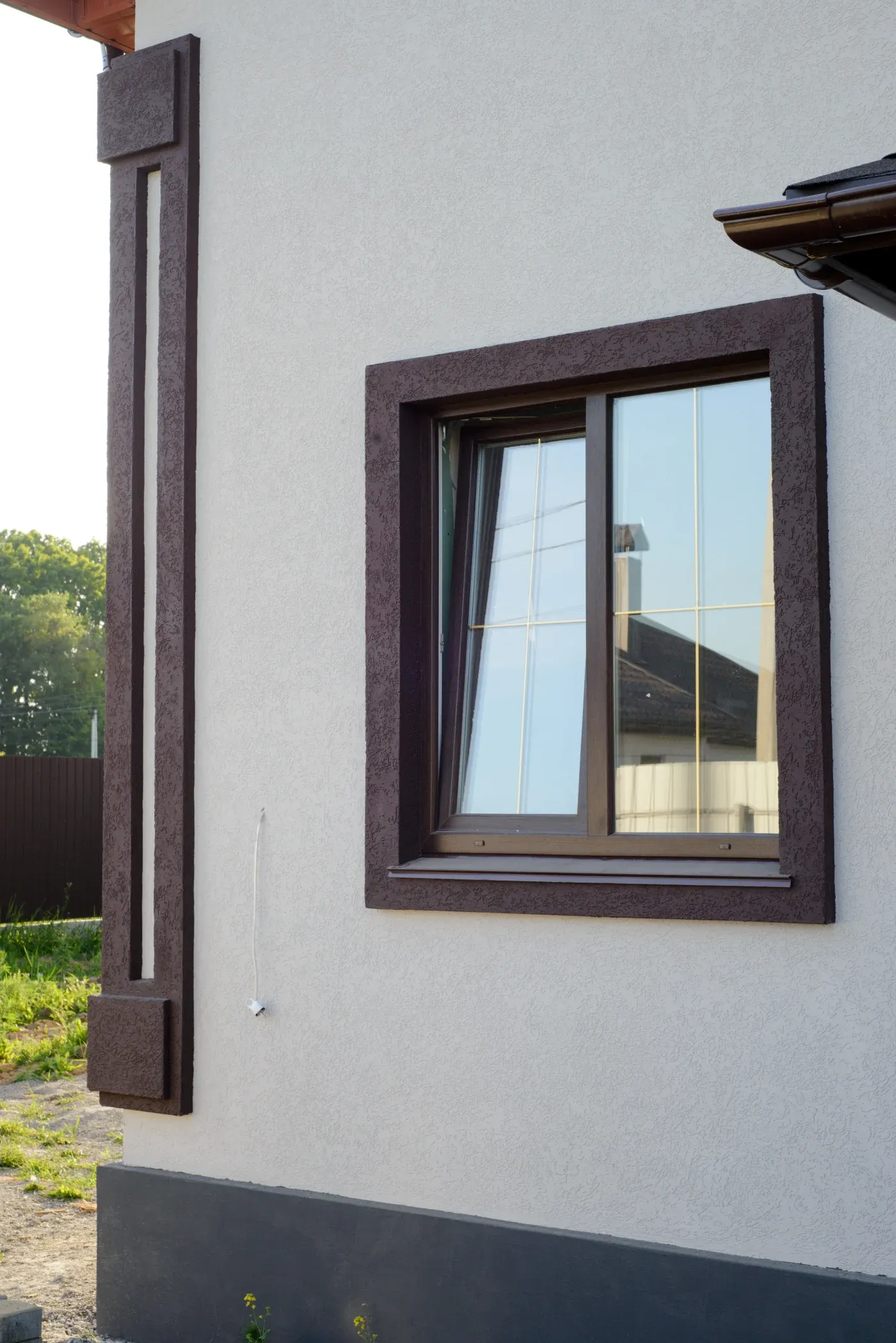 Two windows with a black frame on the side of a stucco house.