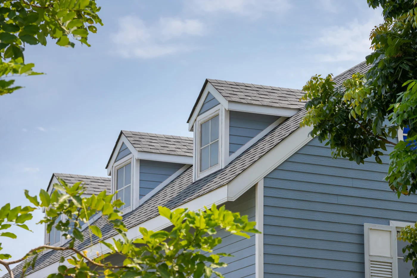 Roof Shingles With Garret House On Top Of The House Among A Lot Of Trees. Dark Asphalt Tiles On The Roof Background Roof Shingles With Garret House On Top Of The House Among A Lot Of Trees. Dark Asphalt Tiles On The Roof Background