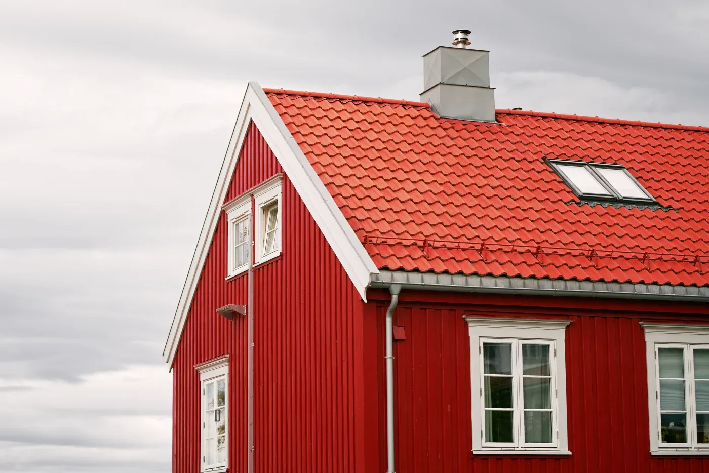 A red roof on a red house with white trim and windows.