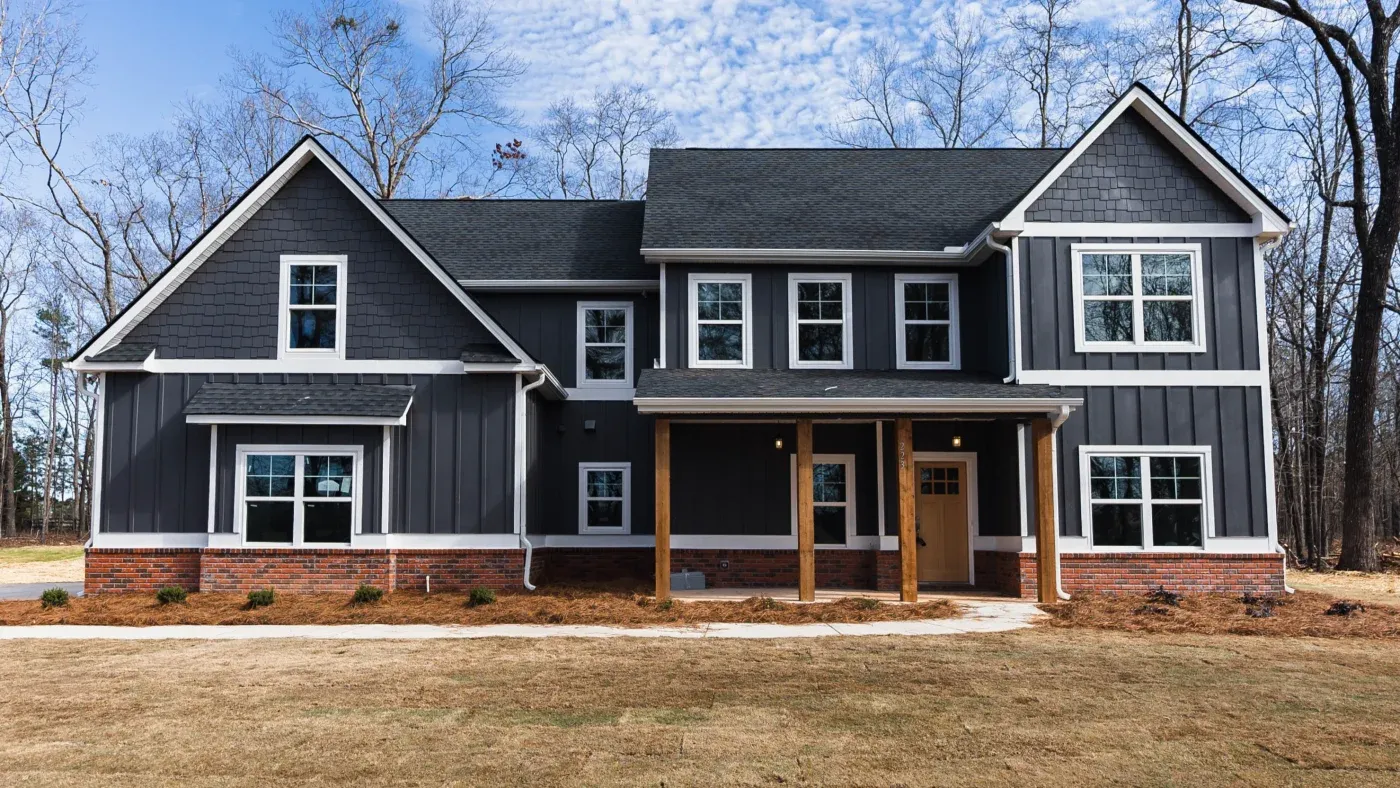 A large house with multiple new white-framed windows and a new wood entry door near Raleigh, NC.