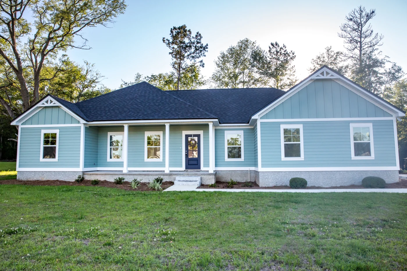Front View Of A Brand New Construction House With Blue Siding, A Ranch Style Home With A Yard Front View Of A Brand New Construction House With Blue Siding, A Ranch Style Home With A Yard