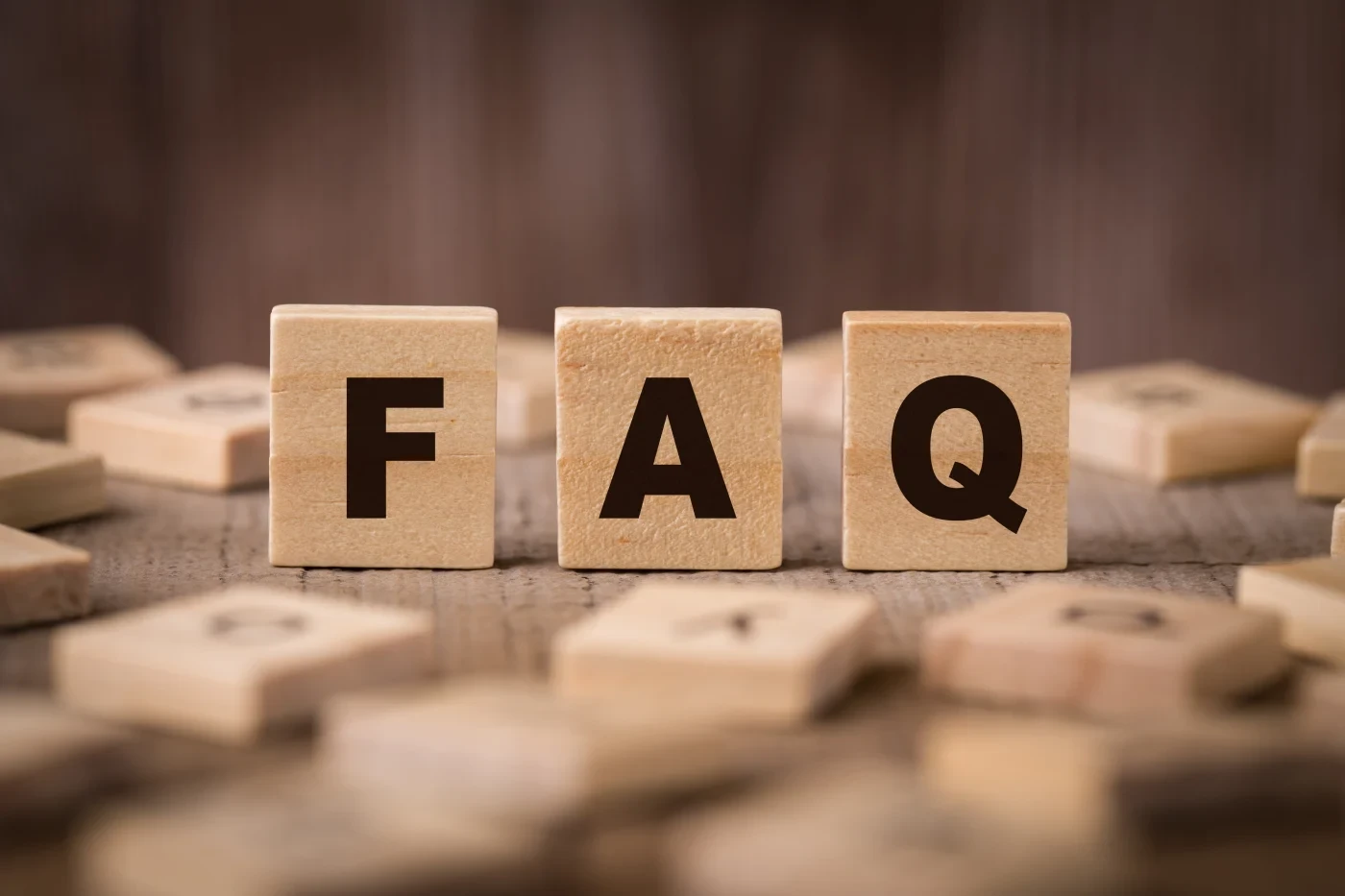 Three wooden blocks with letters arranged to spell “FAQ”