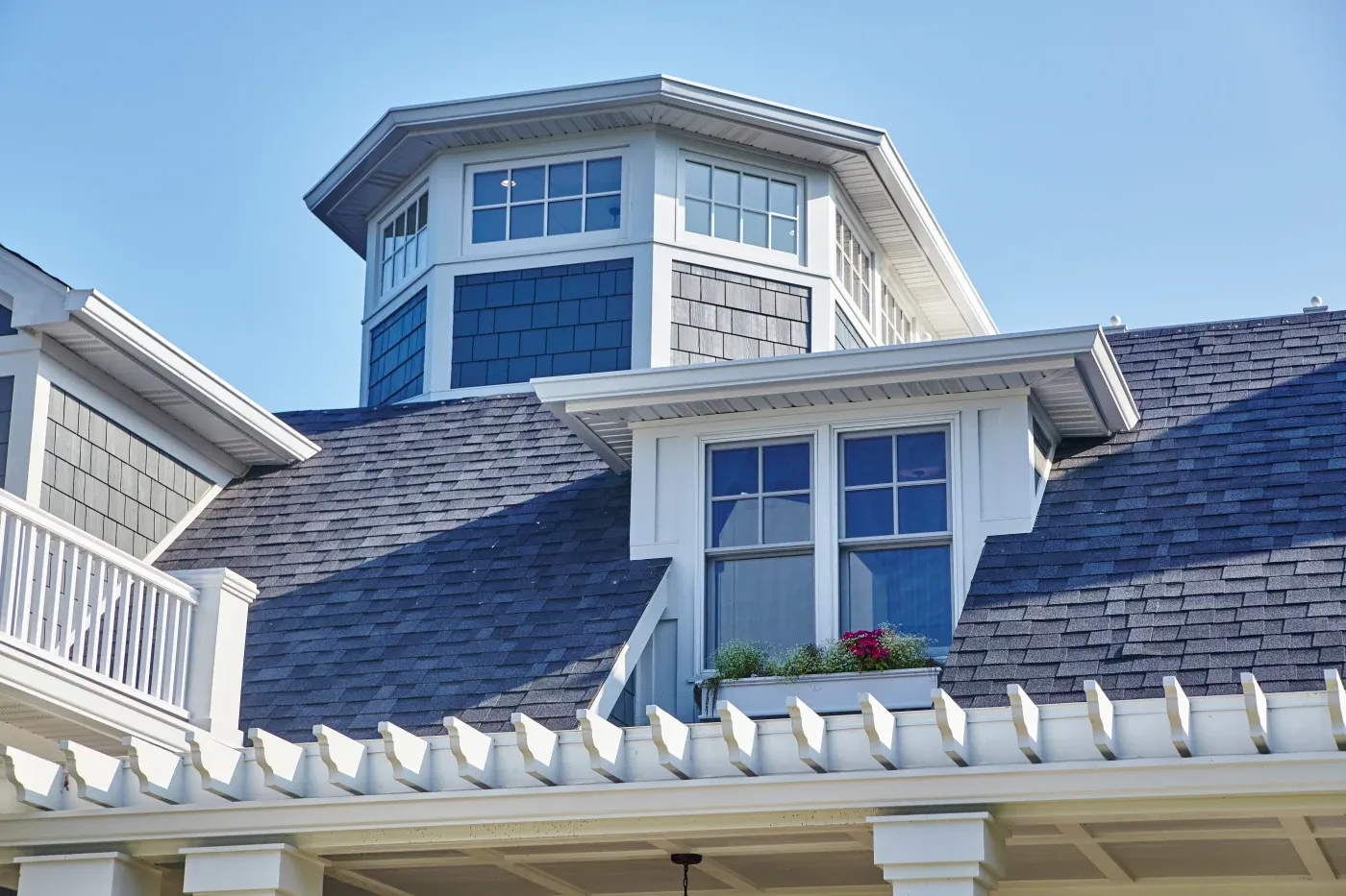 A close-up view of an asphalt shingle roof of a multi-story house.