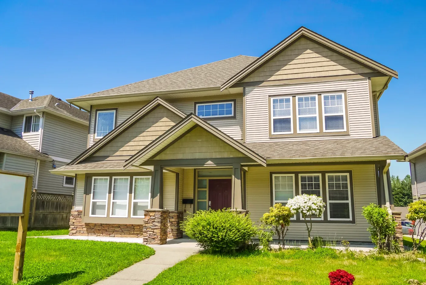 A two-story single-family home with beige siding and a green lawn.