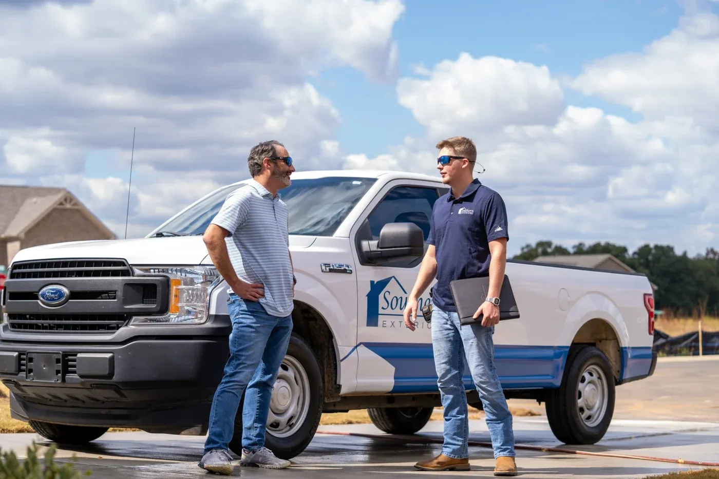 A Southern Exteriors team member talking with a homeowner by a branded truck