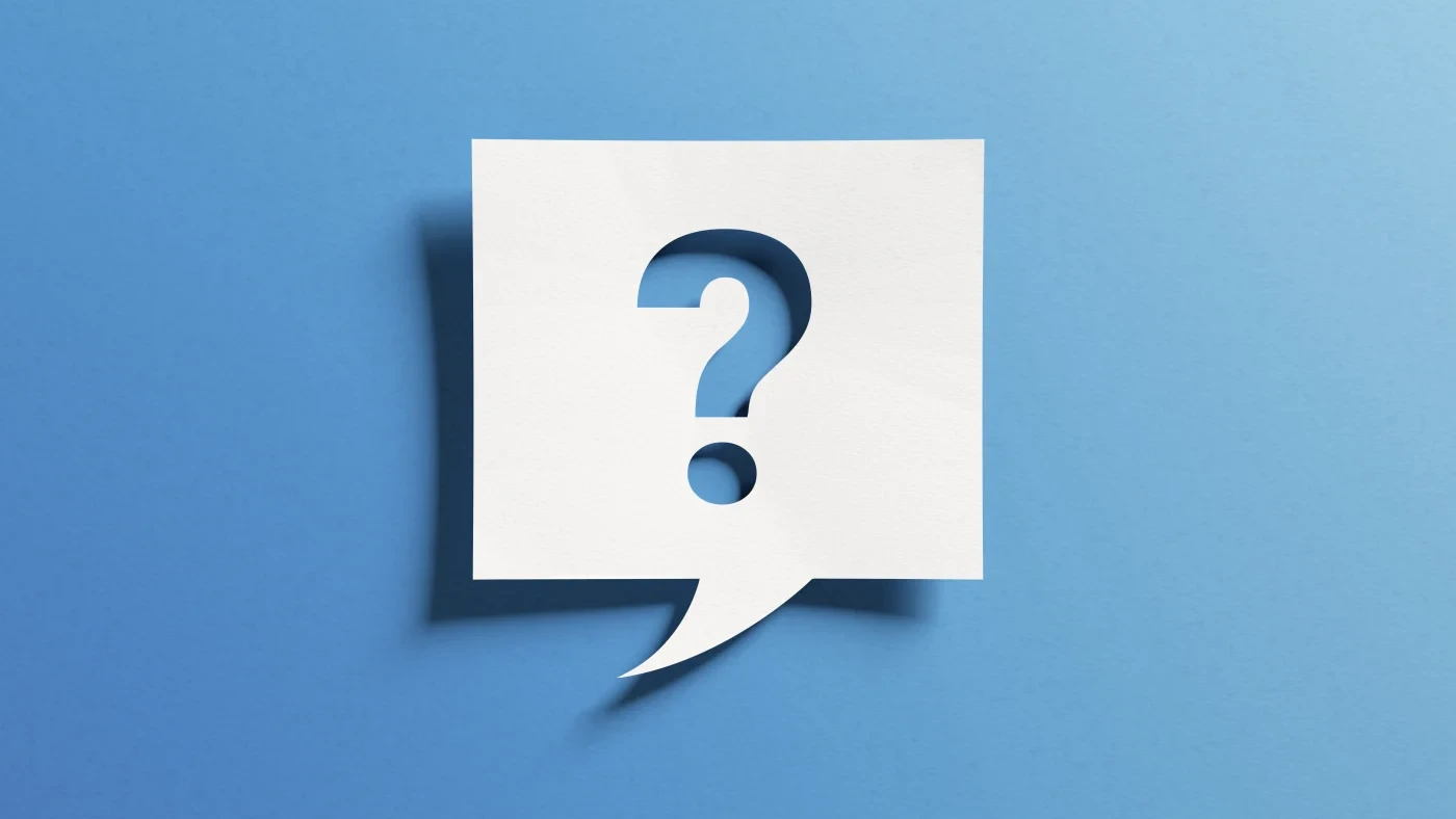 A piece of paper cut into a question mark with a blue background