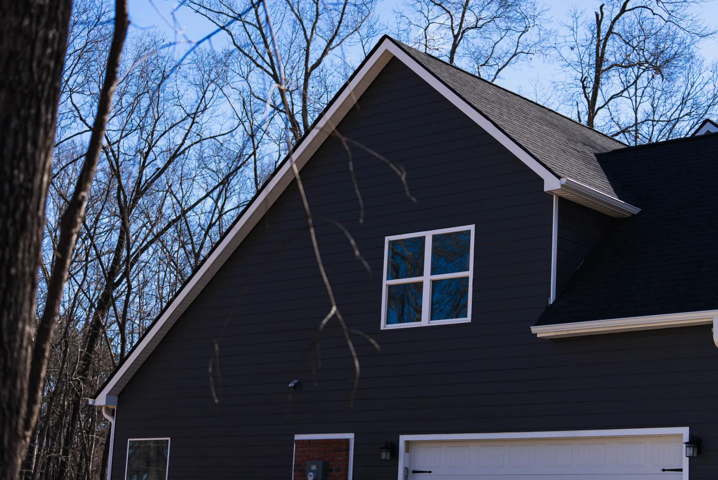 A Charlotte home with an asphalt shingle roof, white garage door, and white-trimmed window